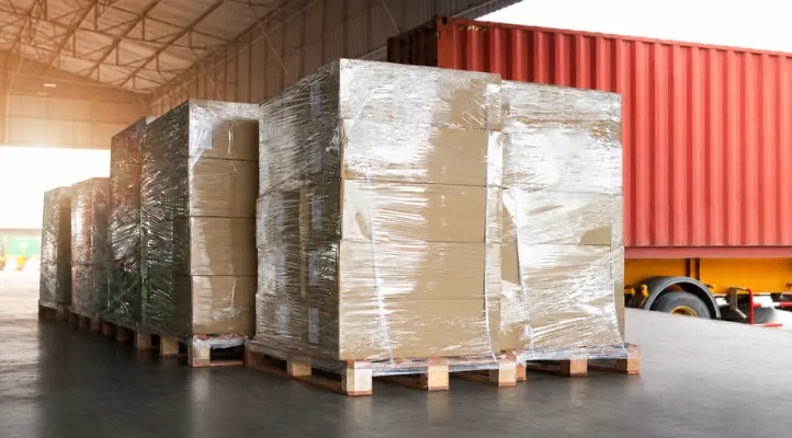 shrink‑wrapped pallets of boxes in a 3pl warehouse loading area